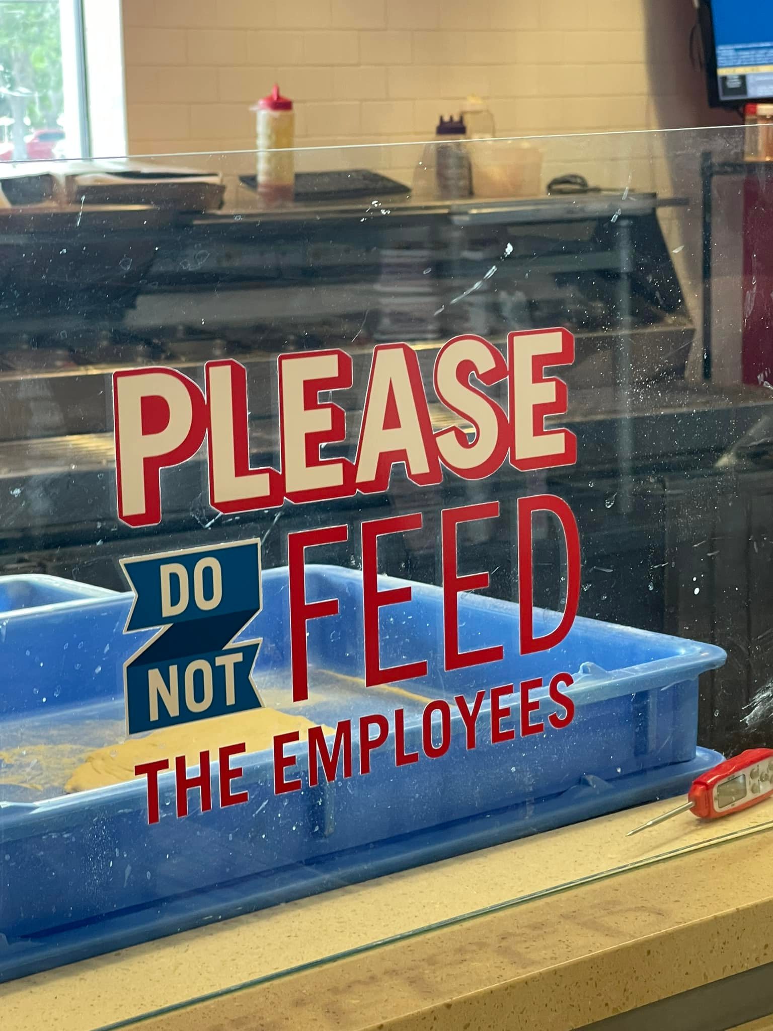 This meme is a play on a common warning sign in kitchens. The image shows a sign with the words "Please do not feed the employees" in a humorous and ironic tone, implying that the employees are the ones who need to be fed, not the customers. The text is often used in a humorous or ironic way to poke fun at the idea that employees are somehow in need of sustenance.